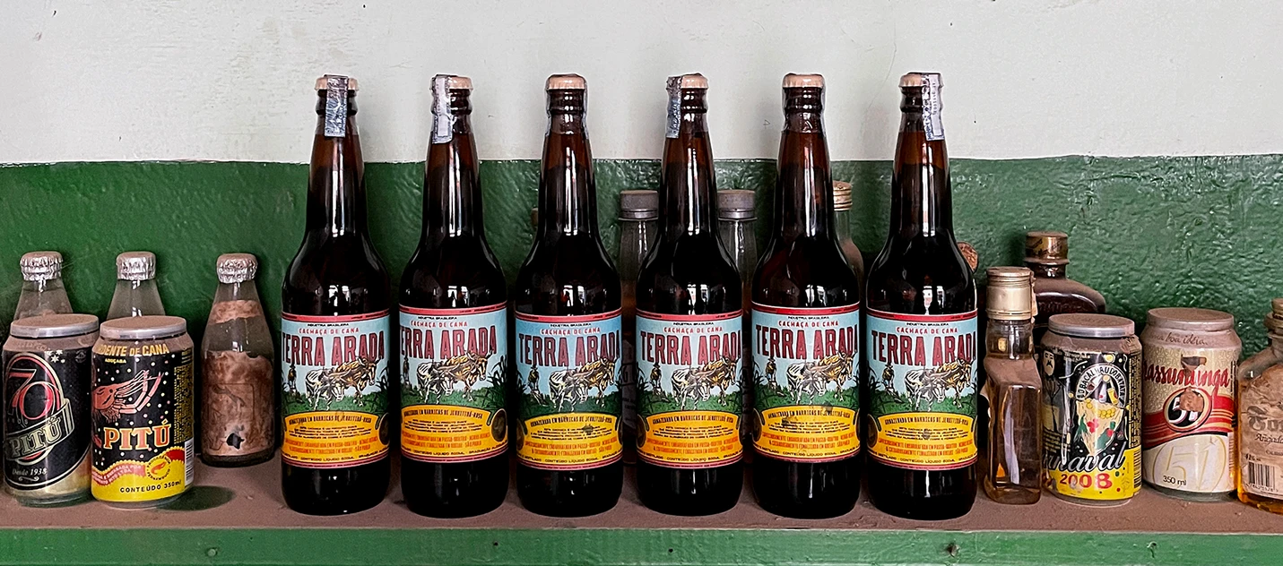 Garrafas da Cachaça Terra Arada com rótulos ilustrados e acabamento em palha de taboa