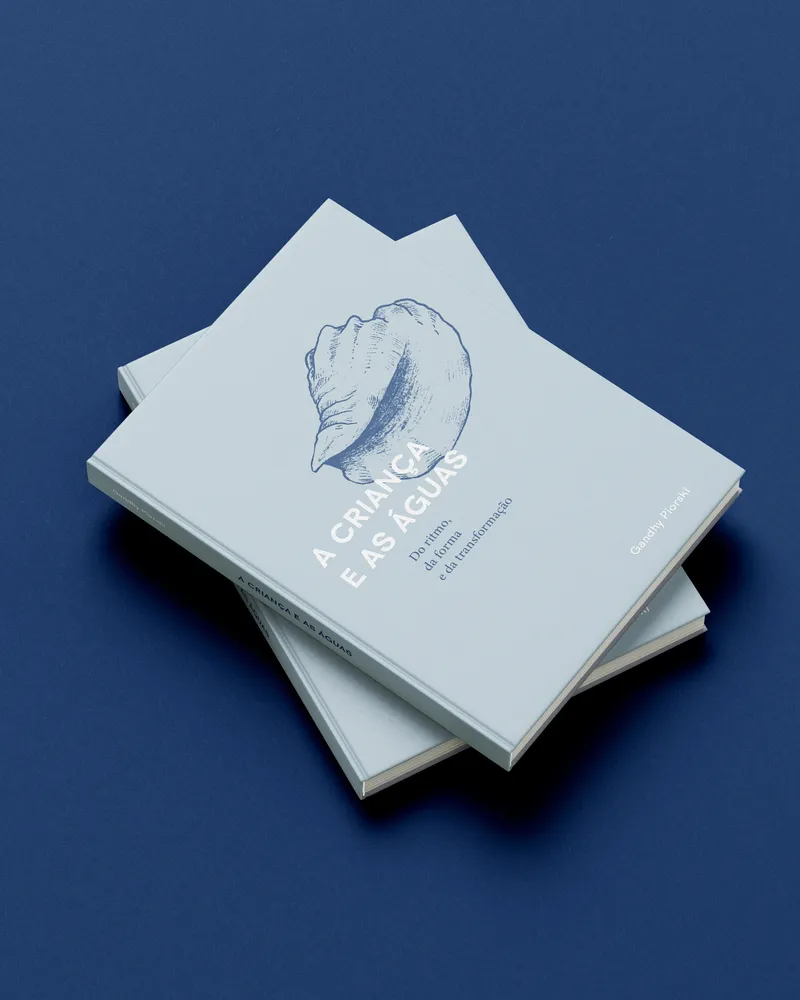 Dois exemplares do livro A Criança e as Águas, de Gandhy Piorski, empilhados sobre fundo azul-marinho