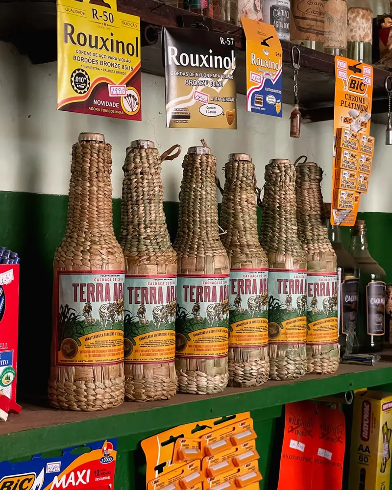 Garrafas da Cachaça Terra Arada com rótulos ilustrados e acabamento em palha de taboa
